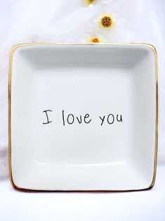 a white square plate with the words i love you written in black ink on it