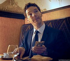 a man in a suit and tie sitting at a table looking at his cell phone