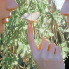 two women are looking at a butterfly on their finger