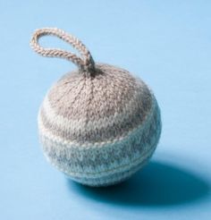 a knitted ball on a blue surface with a string hanging from it's end