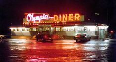 the diner is lit up at night in the rain