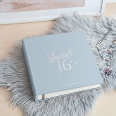 a blue book sitting on top of a furry rug next to a necklace and bracelet