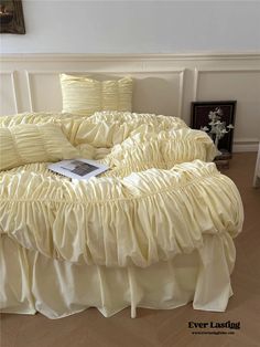 a round bed with ruffles and pillows on it in a room next to a wall