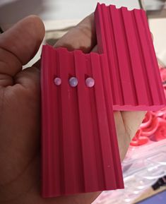 a person holding two pieces of pink plastic