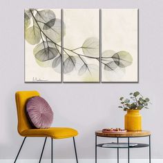 three paintings on the wall in a room with yellow chairs and a vase filled with flowers