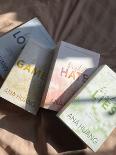 three books sitting on top of a bed next to eachother's name