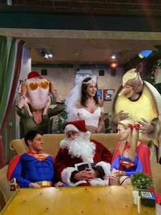 a group of people dressed up as santa clause and other characters sitting around a table