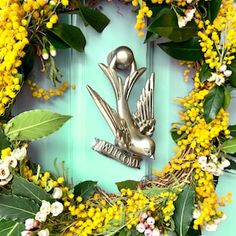 a wreath with flowers, leaves and a bird on it is hanging on the front door