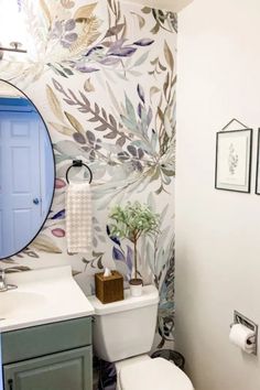 a bathroom with floral wallpaper and a blue door in the shower area is shown