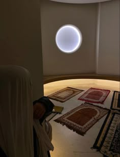 a person laying on the floor in front of rugs and a round light fixture