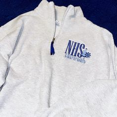 a white sweatshirt with the words n h s on it is laying on a blue blanket