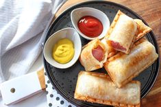 several pastries on a plate with mustard and ketchup