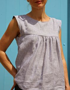 a woman standing in front of a blue wall with her hands on her hips and looking at the camera