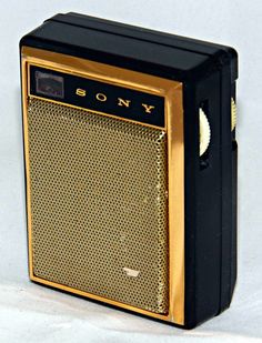 an old fashioned radio sitting on top of a white table next to a black and gold object