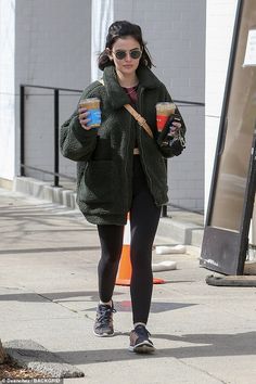 a woman walking down the street with a cup of coffee