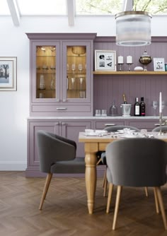 the dining room table is set for two with grey chairs and purple cupboards in the background