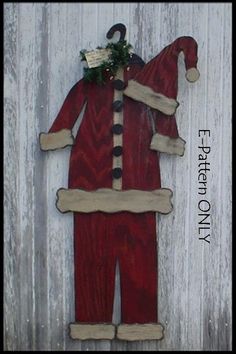 a red santa suit hanging on the side of a wooden wall with decorations around it