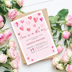 a pink card with hearts on it next to flowers