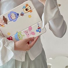 a woman holding a white case with cartoon stickers on it