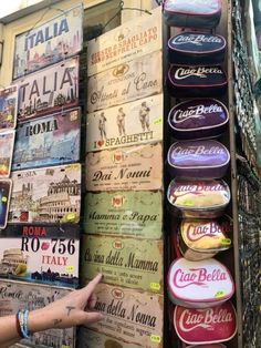 a person pointing at signs on the wall in front of a building with many different colors and sizes