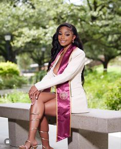 a woman sitting on top of a cement bench wearing a purple satin sash and heels