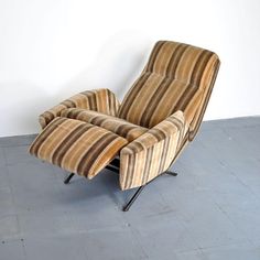 a striped chair sitting on top of a cement floor next to a white walled wall