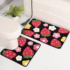 two bathroom mats with strawberries and daisies on them next to a white toilet