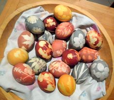 a wooden bowl filled with painted eggs on top of a table