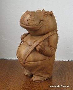 a wooden statue of a frog holding a watering can on top of a wood floor