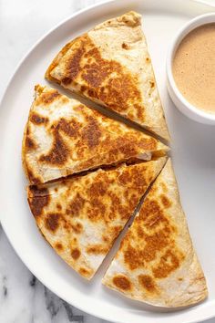 a white plate topped with quesadillas next to a cup of coffee