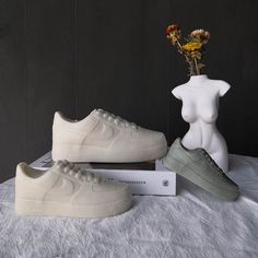 a pair of white shoes sitting on top of a table next to a vase with flowers