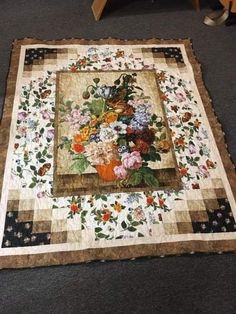 a quilted table runner with flowers on it and a wooden chair in the background