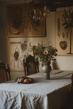 a dining room table with flowers in a vase and bread on the table next to it