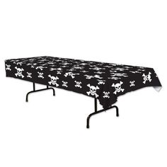 a black table cloth with white skulls and crossbones is on top of an ironing board