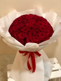 a bouquet of red roses wrapped in white paper