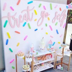 a dessert table with lots of treats and confetti on the wall behind it