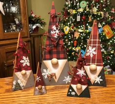 three wooden christmas trees with snowflakes on them and decorations in front of a christmas tree