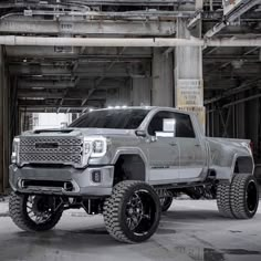 a silver truck is parked in an industrial area with large tires and rims on it