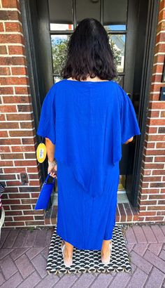 a woman standing in front of a door with her back to the camera and holding a blue frisbee