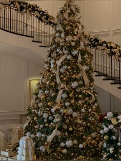 a decorated christmas tree in the middle of a room with white and gold decorations on it