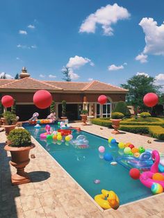 an inflatable pool surrounded by balloons and potted plants on the side of a house