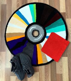 a pair of black shoes sitting on top of a wooden floor next to a colorful rug