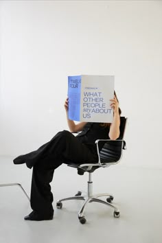 a woman sitting in an office chair holding up a book that reads what the people us about