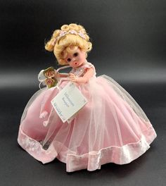 a doll is dressed in a pink dress and holding a white tag that says, i love you