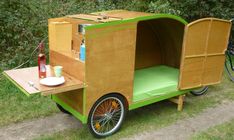 a small cart made out of wood with a green seat and side table on the back