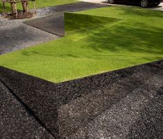 an empty parking lot with grass in the middle and cars parked on the other side