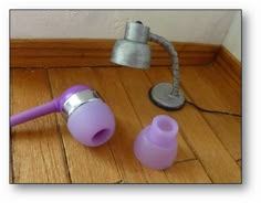 a purple hair dryer sitting on top of a wooden floor next to a lamp