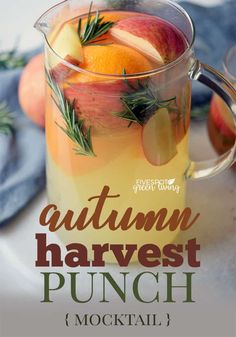 an autumn harvest punch in a pitcher with apples, oranges and rosemary garnish