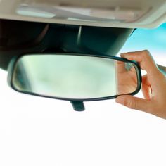 a person's hand is holding the side mirror of a car