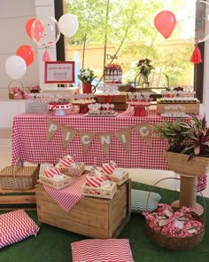 a table set up with red and white checkered cloths, picnic food and decorations